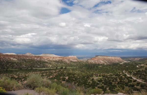 Expansive desert landscape featuring layered mesas under a cloudy sky